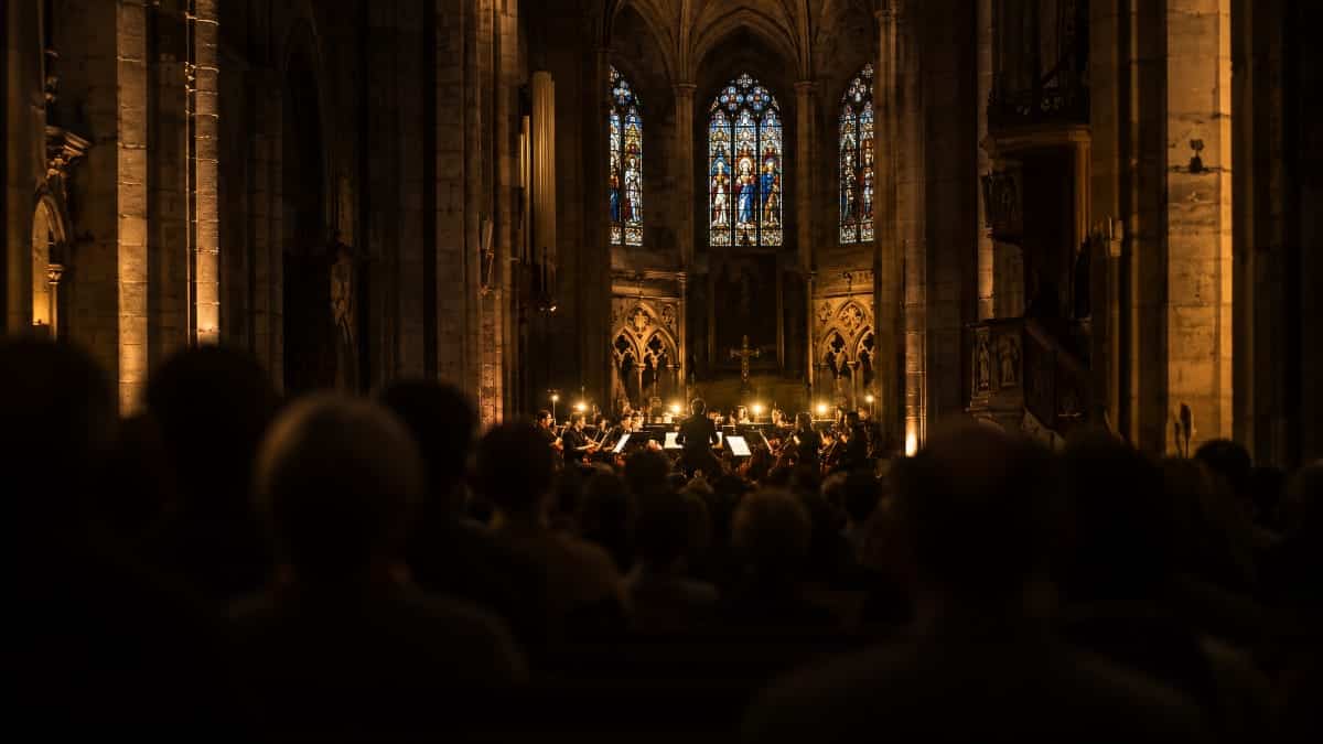 Ambiance d'un concert symphonique dans un édifice religieux, lumière chaude sur les musiciens
